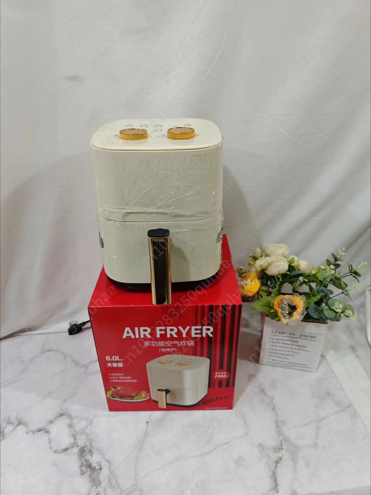 Cream countertop air fryer with gold pull handle, shown with retail box