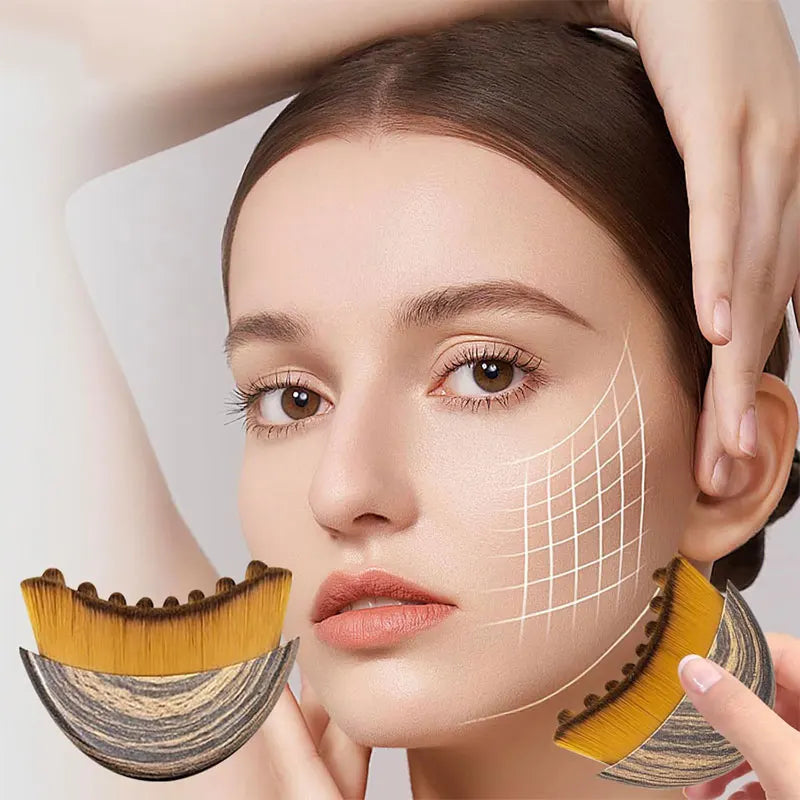 A woman uses a crescent-shaped face brush with a wood-grain handle and soft, dense bristles to contour her jawline.