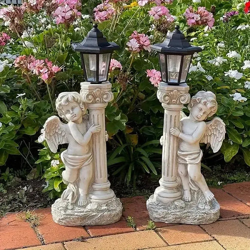 Two white stone-finish cherub statues holding columns topped with black solar lanterns in a garden.