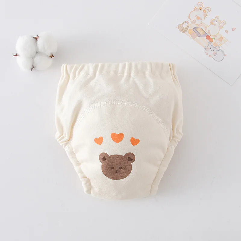 Cream-colored cotton baby training diaper with cute bear and orange heart design for comfortable baby care.