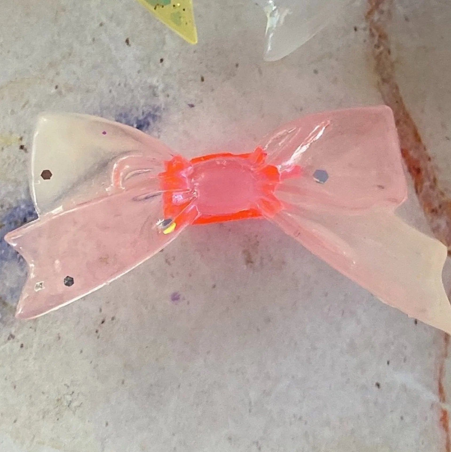Pink glitter bow dust plug for Tamagotchi Uni. Protective silicone accessory for electronic pet ports.