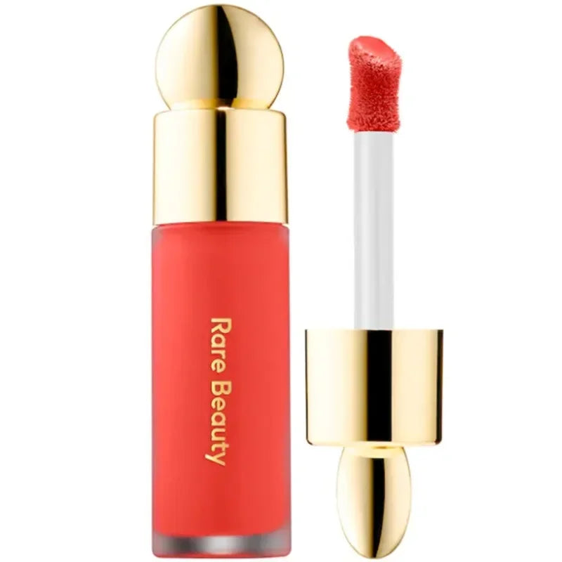 Rare Beauty matte liquid lipstick in vibrant coral with a gold cap and precise applicator for a smooth, rich finish.