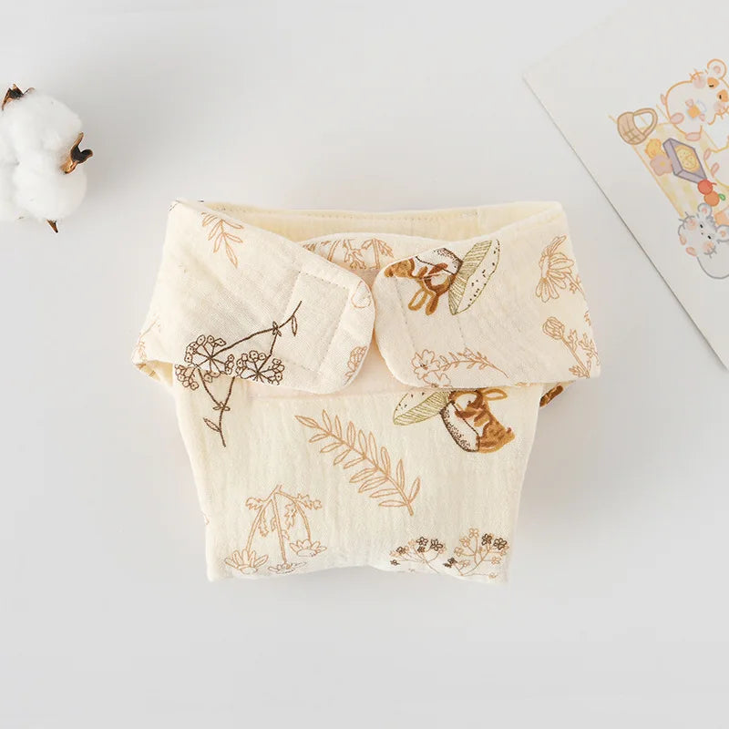 Reusable muslin baby diaper with cream mushroom and floral print, featuring adjustable hook-and-loop closure.