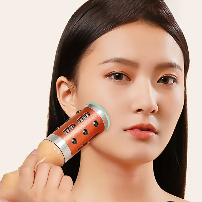 Woman using a copper-toned, cylindrical moxibustion roller with a wooden handle on her cheek for skincare.