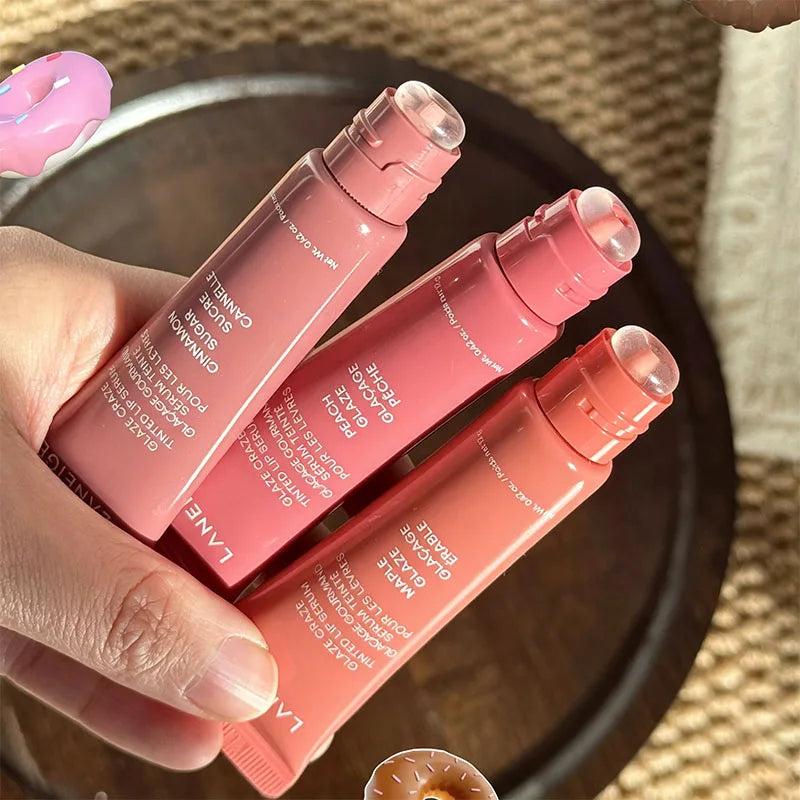 Hand holding three Laneige Glazey tinted lip serum tubes in pink, peach, and maple shades with glossy applicator tips.