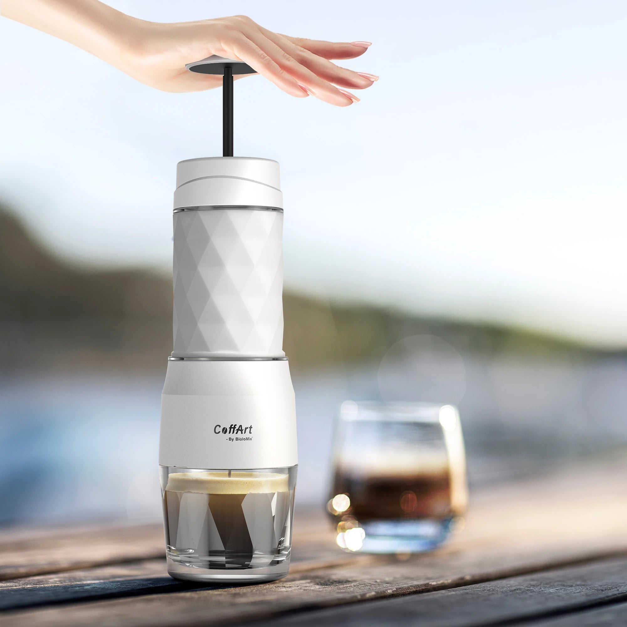 CoffArt by BioloMix portable manual espresso maker in white with textured geometric design on wooden table.