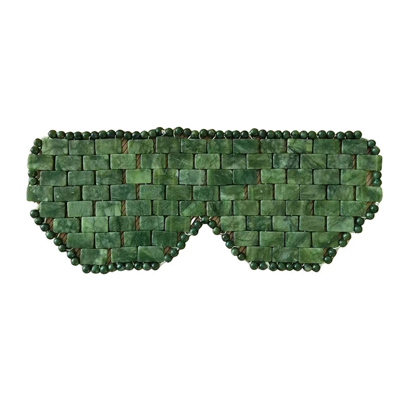 Green natural jade stone eye mask for cooling spa therapy, facial massage, and relaxation sleep aid on white background.