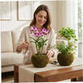 Handmade moss ball planters on a table with faux flowers and greenery, home decor.