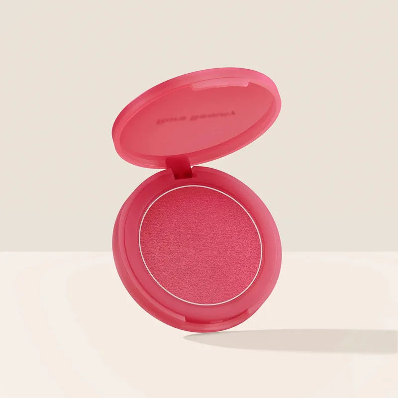 Rare Beauty powder blush in bright pink matte finish with smooth, soft-touch texture in a matching compact case.