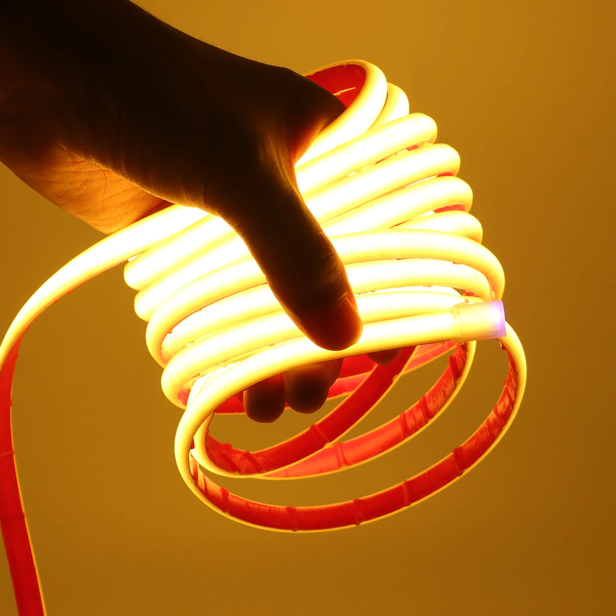 Waterproof COB LED neon strip light glowing amber, held in hand