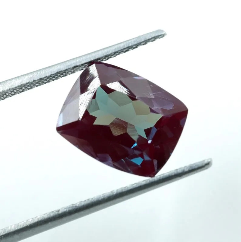 Faceted cushion-cut alexandrite gemstone, maroon-red with hints of teal color change