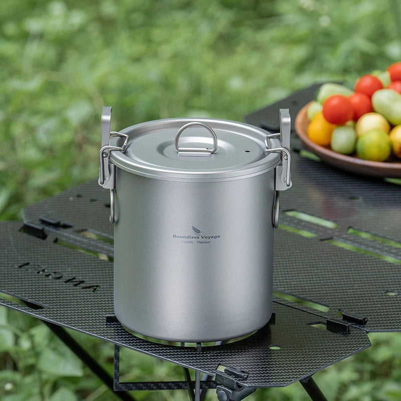 Titanium rice cooker pot with metal handles and domed lid on a camping stove