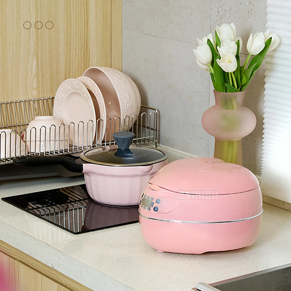 Pink mini rice cooker on countertop with lid closed, front control buttons visible