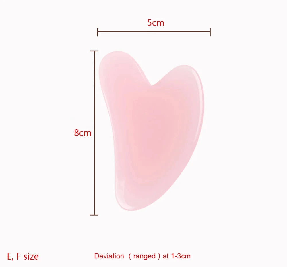 Heart-shaped light pink resin Gua Sha facial massage tool, 8cm by 5cm, isolated on a white background.