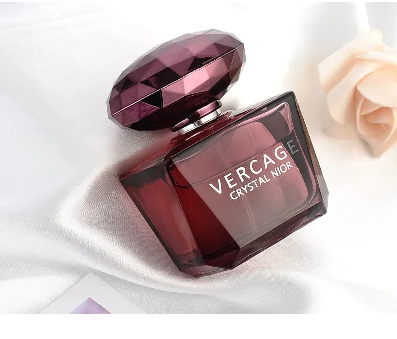 Luxury dark red glass perfume bottle with faceted cap on white satin, 50ml floral scent for women.