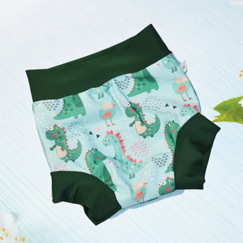 Small dinosaur print baby swim diaper with green trim on a light blue background.