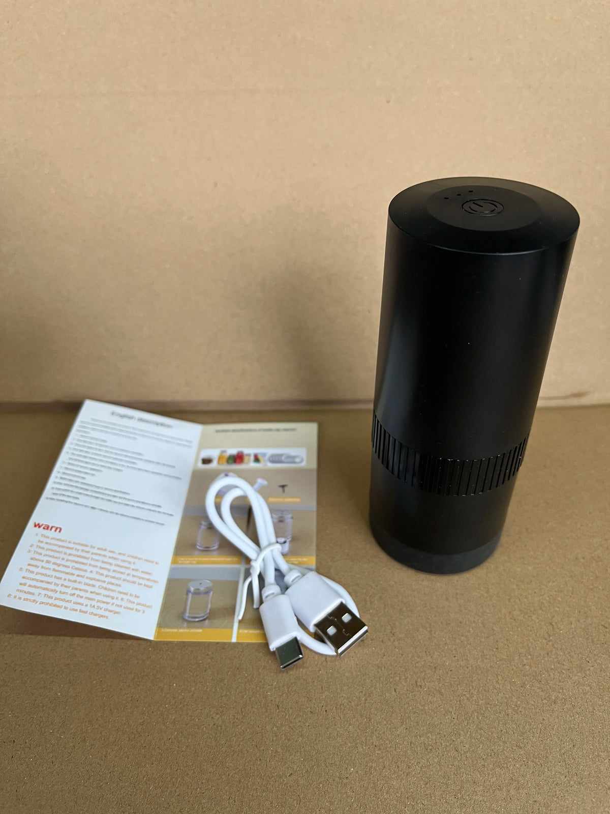 Black cylindrical vacuum sealer with USB cable and instruction papers