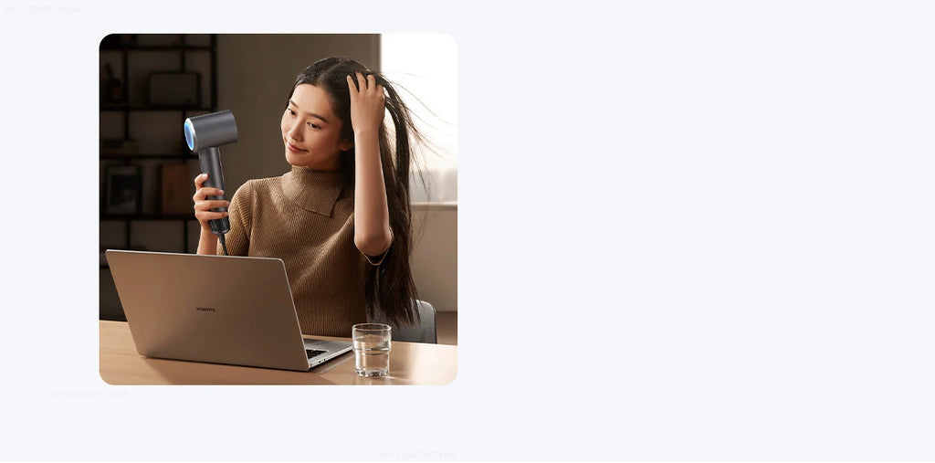 Woman using grey Mijia H501 high-speed ionic hair dryer for fast, professional drying at her desk.