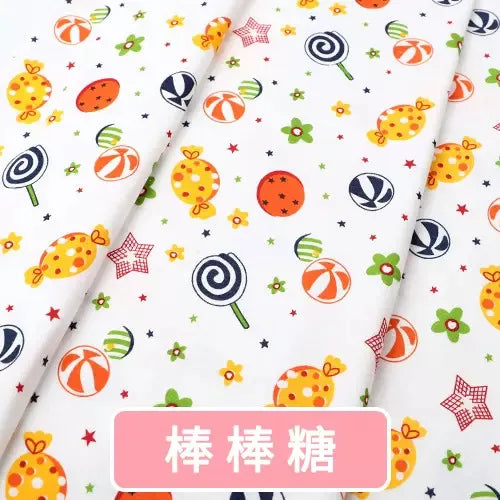 White organic knit jersey fabric featuring a colorful print of lollipops, candies, stars, and flowers by Tidesmit.