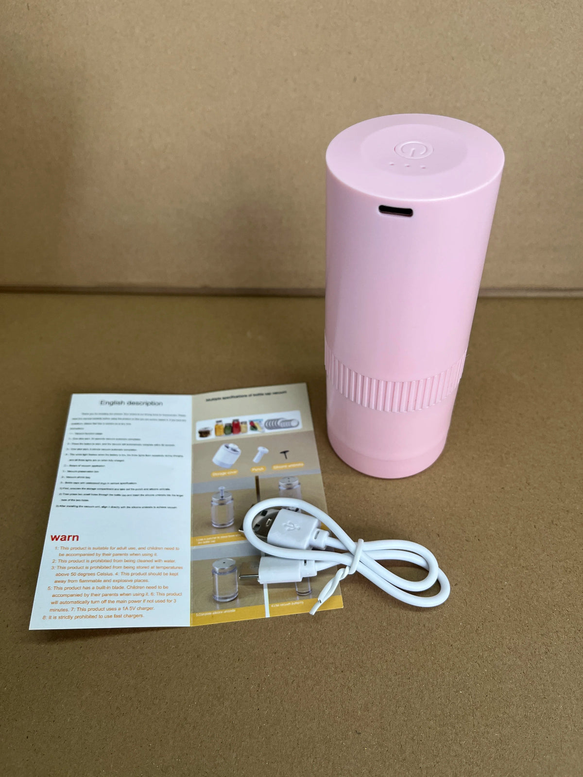 Pink cylindrical vacuum sealer with USB cable and instruction papers