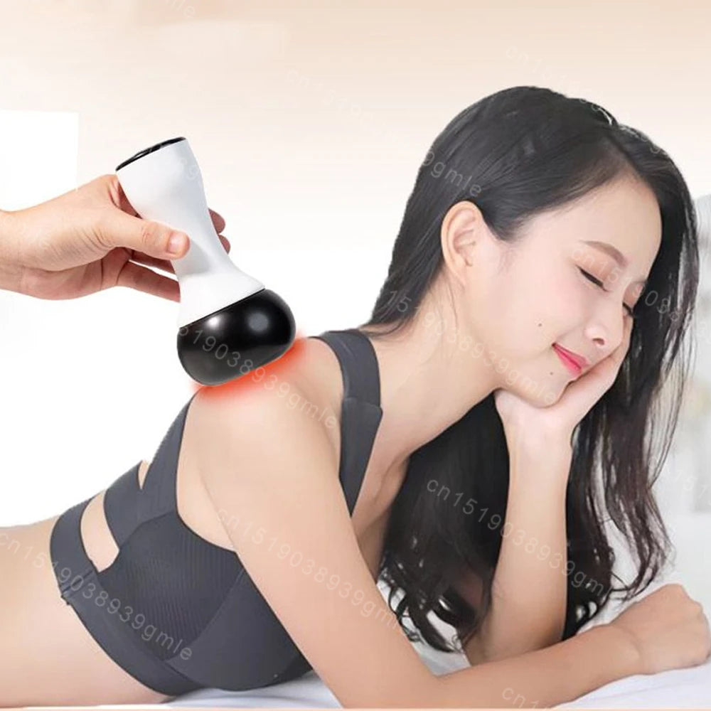 A hand uses a white and black electric Bian stone Gua Sha massager to apply a red hot compress to a woman's shoulder.
