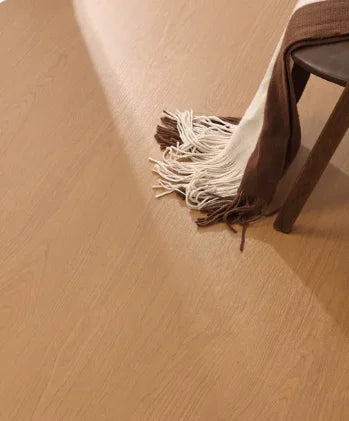 SPC click flooring plank surface with warm light wood grain and chair leg detail
