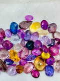 Loose multicolor sapphire gemstones pile of faceted oval and round stones