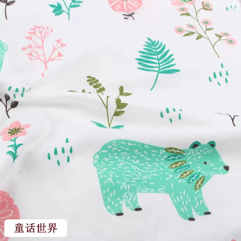 White organic knit jersey fabric with a whimsical print of green bears, pink flowers, and botanical leaves.
