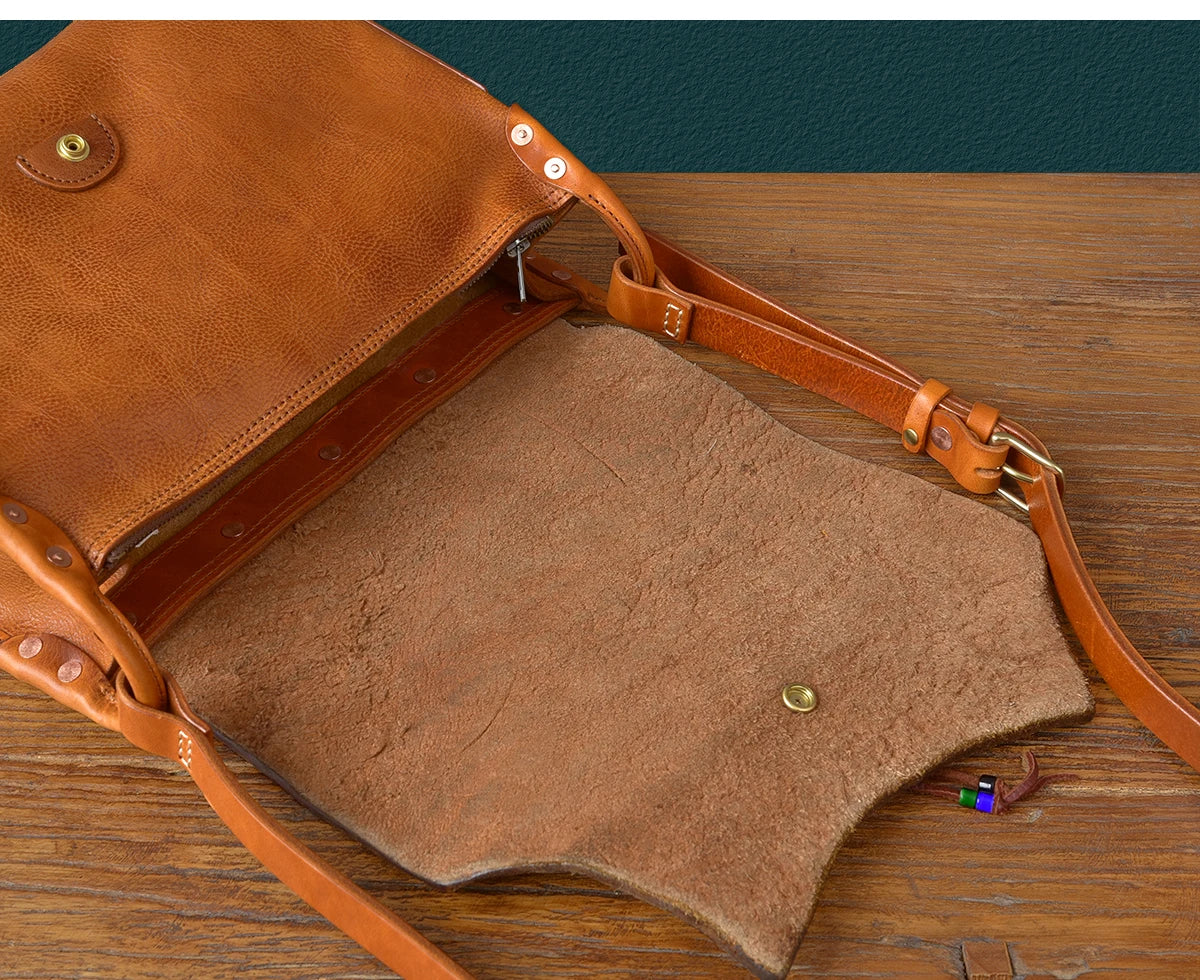 PNDME handmade vintage tan genuine cowhide leather messenger bag with adjustable shoulder strap and brass stud detailing.