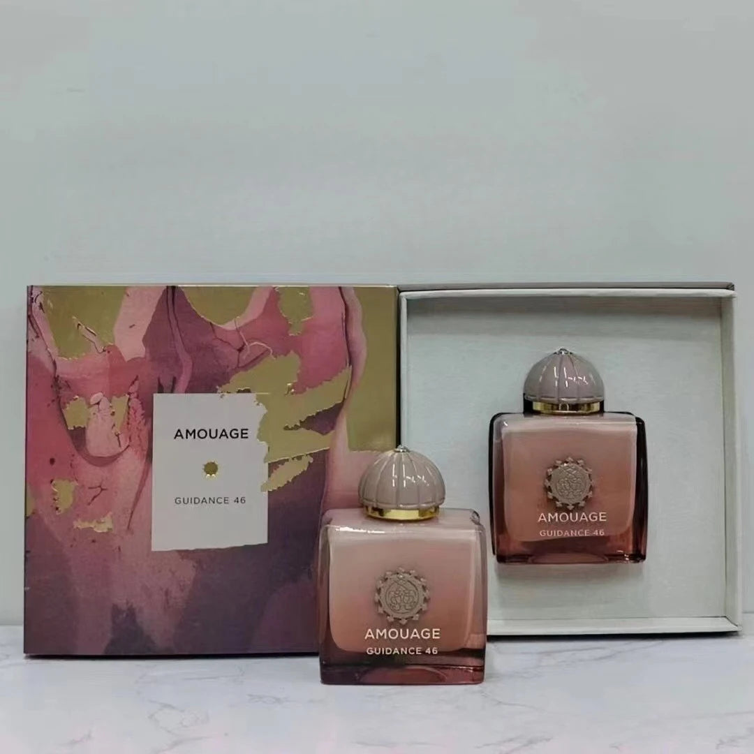 Amouage Guidance 46 floral perfume bottles in ombre pink glass with metallic gold accents in a decorative gift box.