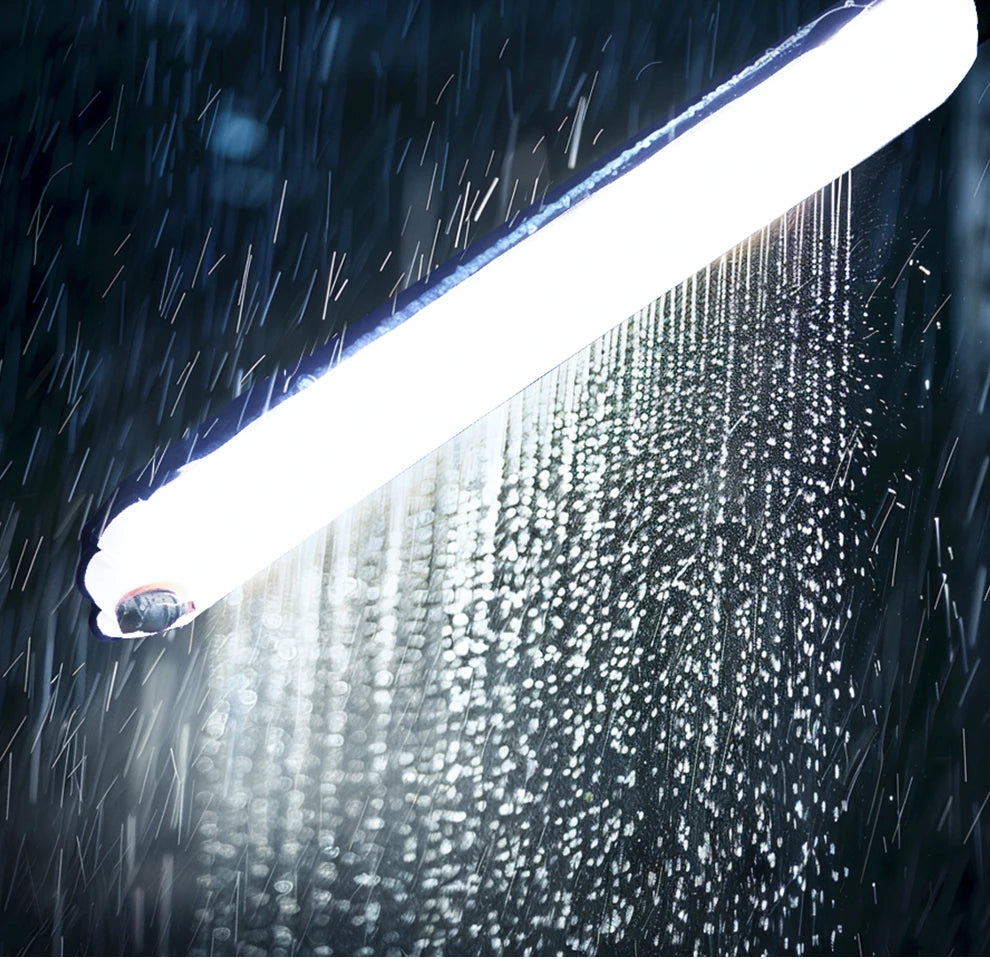 Waterproof LED linear shop light emitting bright white light during heavy rain.
