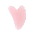 A smooth, translucent light pink heart-shaped resin gua sha massage tool on a white background.