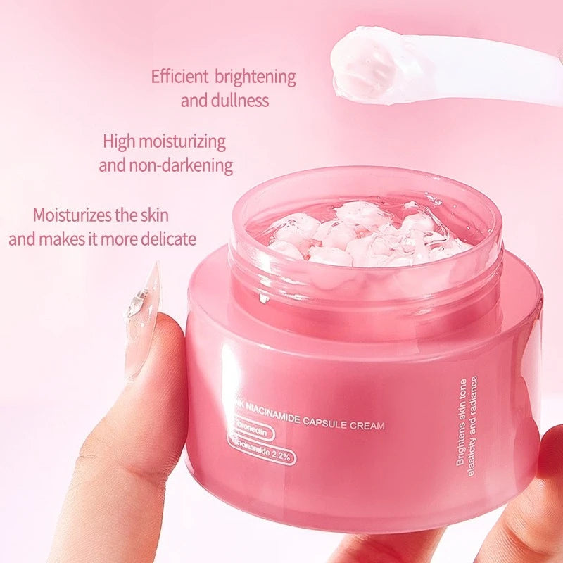 Open jar of pink Niacinamide capsule face cream with a spatula, held by a hand. Soft pink aesthetic.