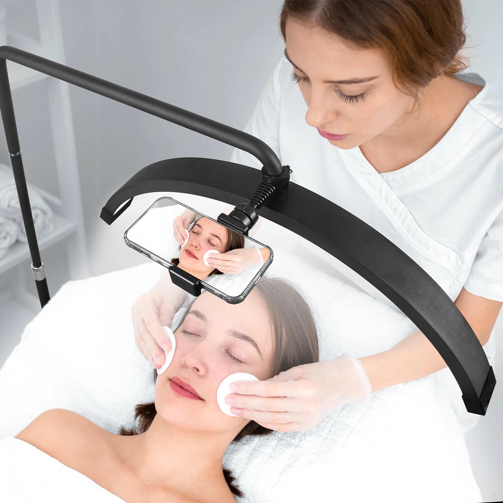 Black arched beauty light with a smartphone mount, used for recording skincare or cosmetic treatments.