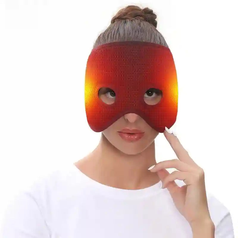 A woman wears a red, air-layer textured heating mask covering her eyes, with glowing side panels against white.