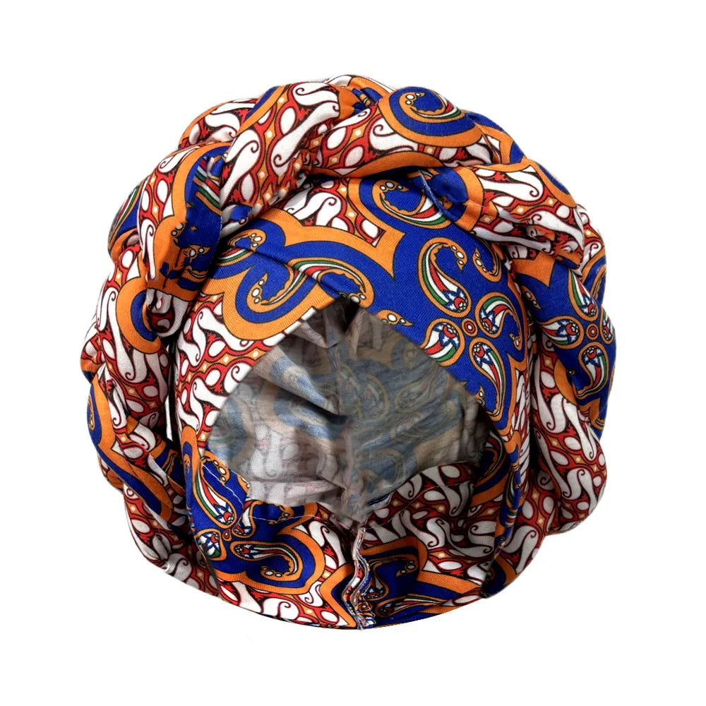 Tidesmit round turban bonnet in vibrant blue, orange, and white paisley print with a braided knot top design.