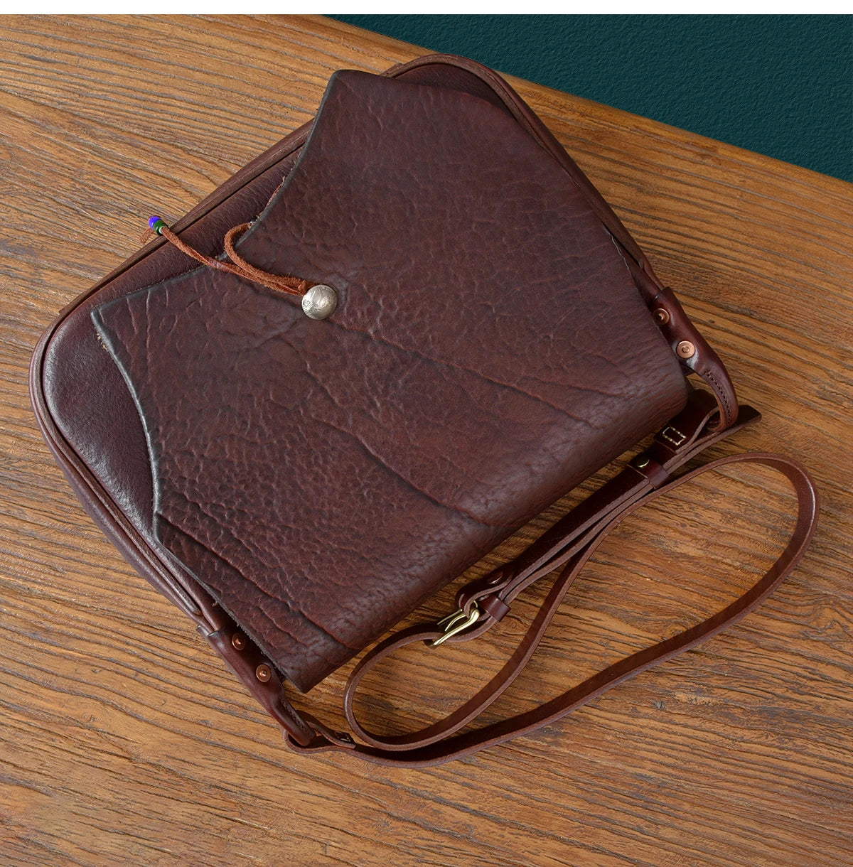 Vintage handmade dark brown cowhide messenger bag with a single button closure and adjustable leather shoulder strap.