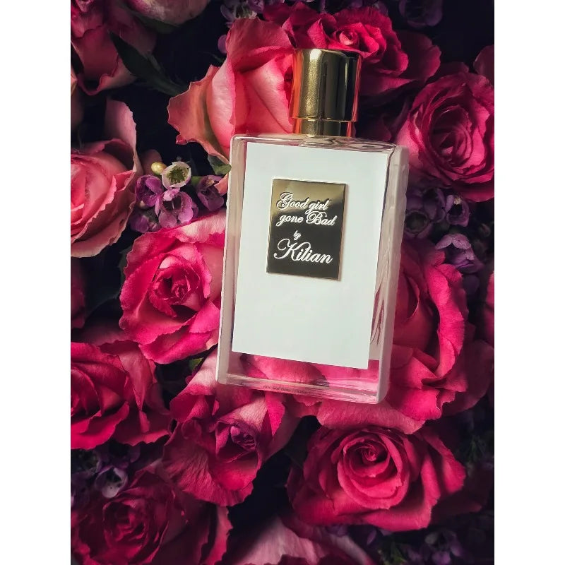 Kilian Good Girl Gone Bad EDP: Floral unisex perfume in a white rectangular bottle on a bed of fresh pink roses.