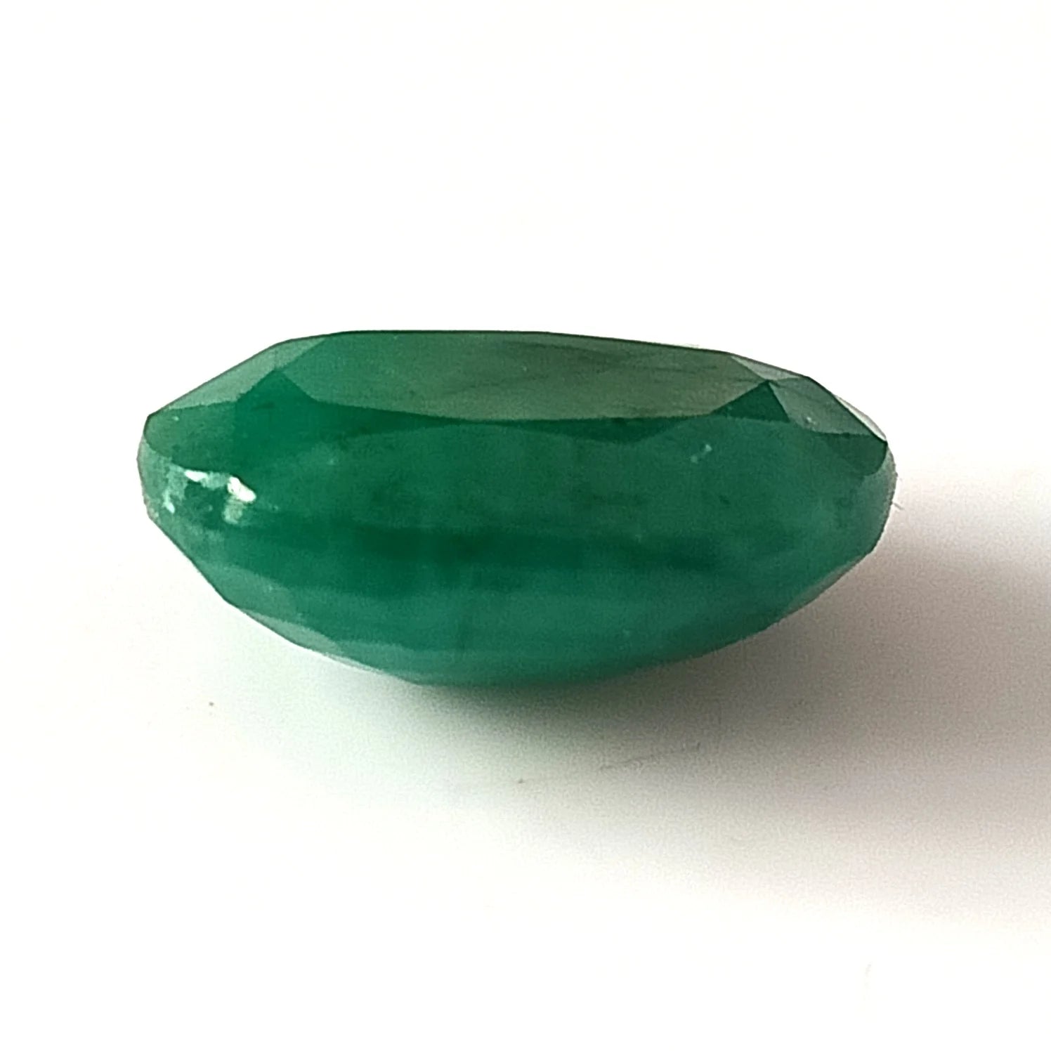 Faceted oval green emerald gemstone, top view showing gemstone facets