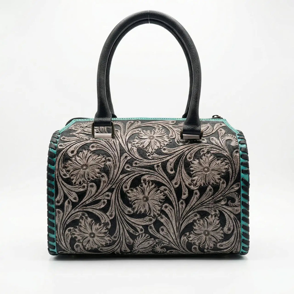 Luxury black leather mini duffel trunk with teal floral tooling, double handles, and whipstitch trim.