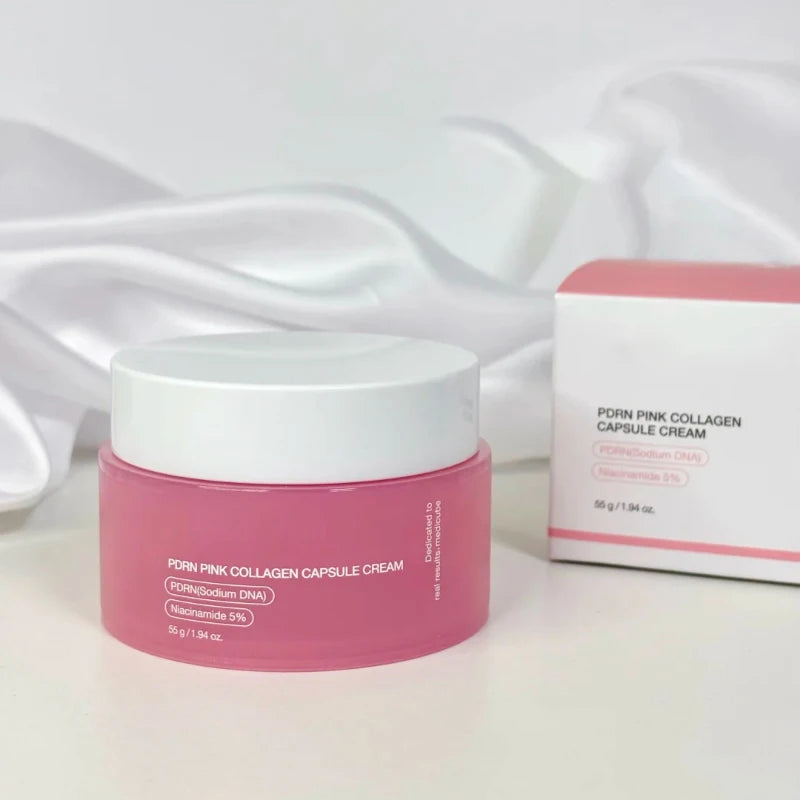 Pink face cream jar and boxed container set on a light fabric surface