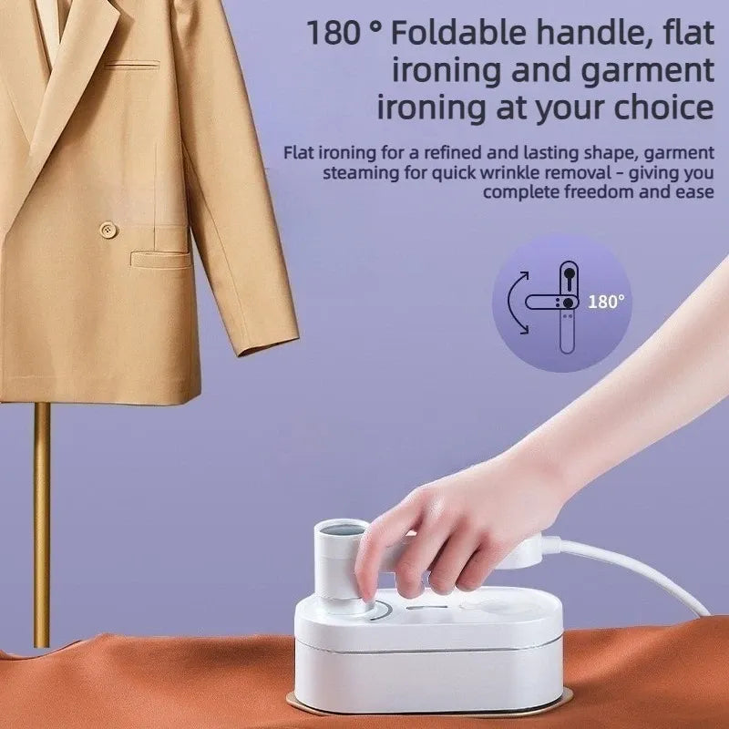 Handheld garment steamer with 180° foldable handle smoothing fabric flat on a surface with a tan blazer hanging nearby.