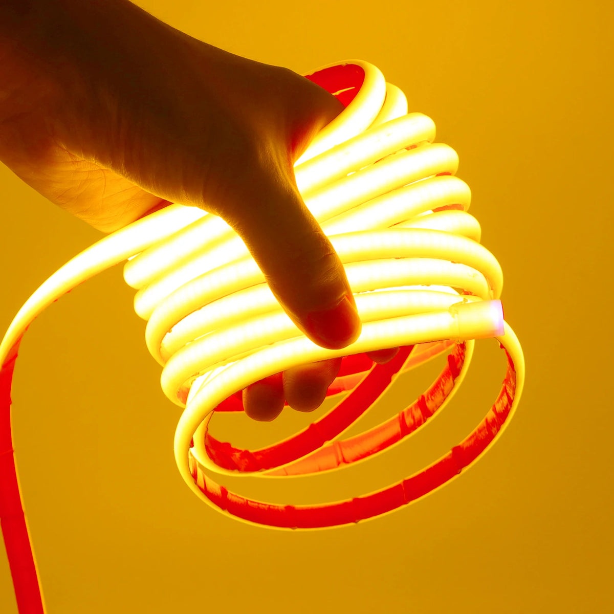 Flexible LED neon tape light with warm white glow, spiral coil held in hand