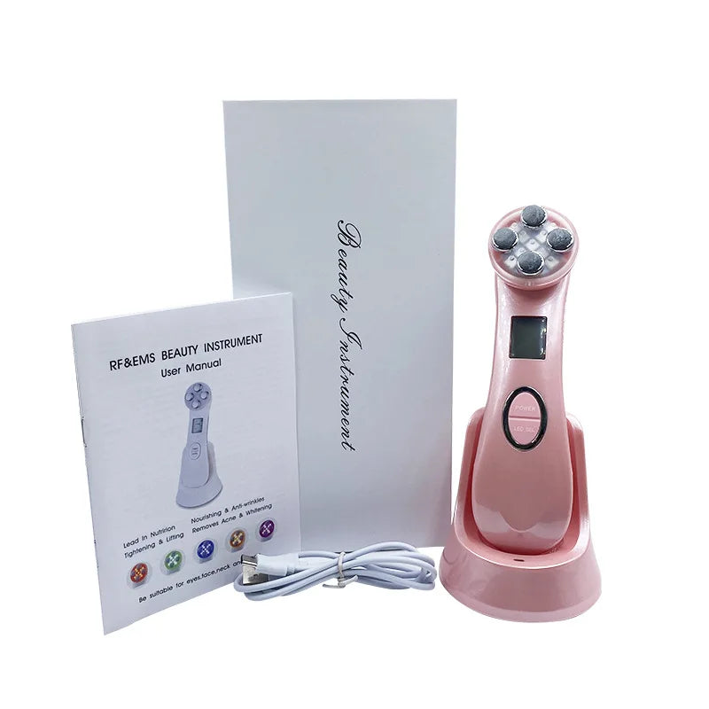 Pink handheld facial beauty device with charging base, power cord, user manual, and white box packaging.