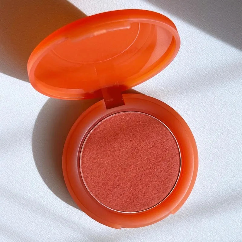 Rare Beauty powder blusher in a vibrant coral orange shade with a smooth, soft-matte texture in a compact case.
