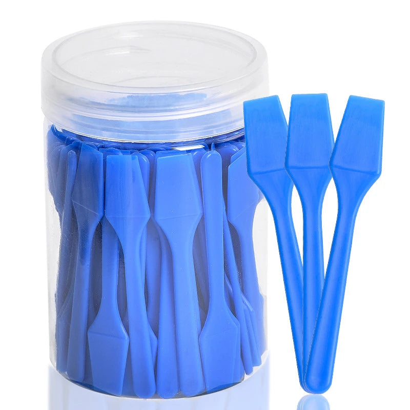 A clear plastic jar filled with 100 blue, mini, spade-shaped plastic cosmetic spatula scoops.