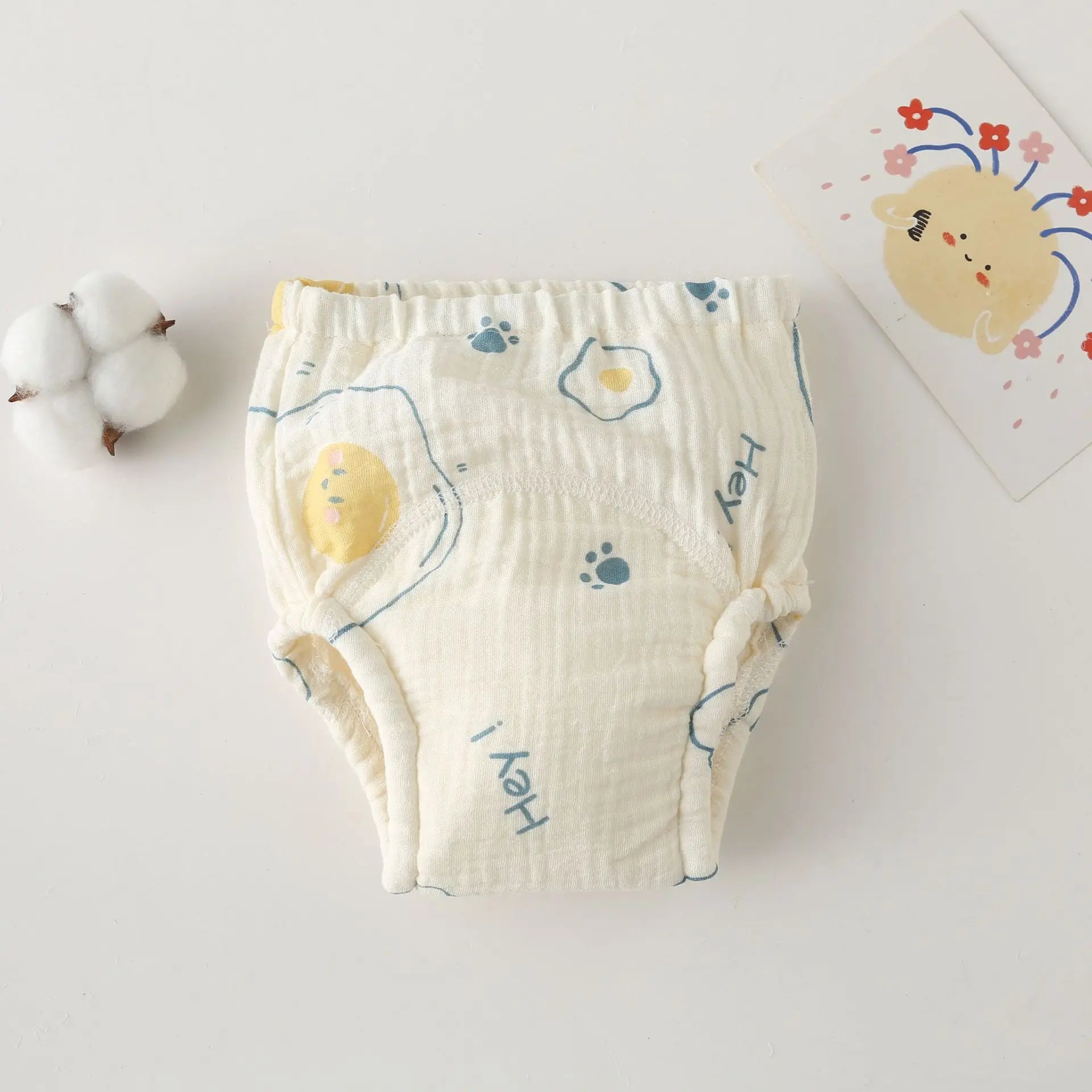 Baby care training diaper in cream cotton with egg and paw print design.