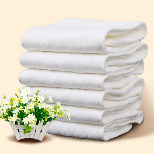 Stack of 5 white quilted baby cloth diaper inserts next to a small pot of flowers. Soft newborn care essential.