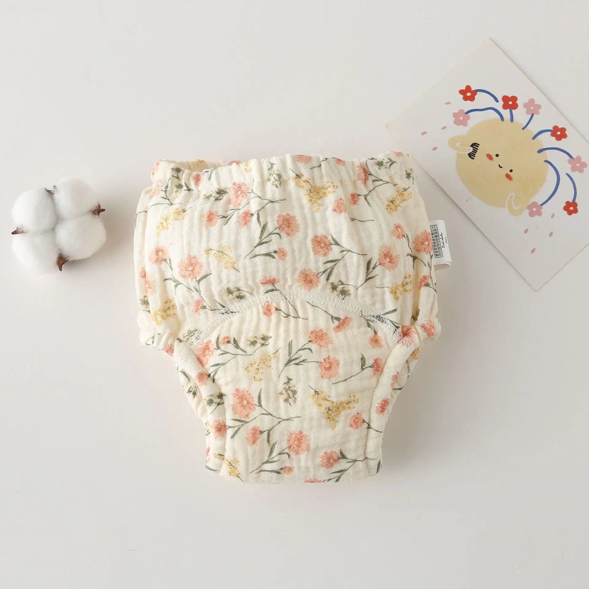 Floral muslin baby training diaper with cotton texture and ruffled waistband for soft baby care.
