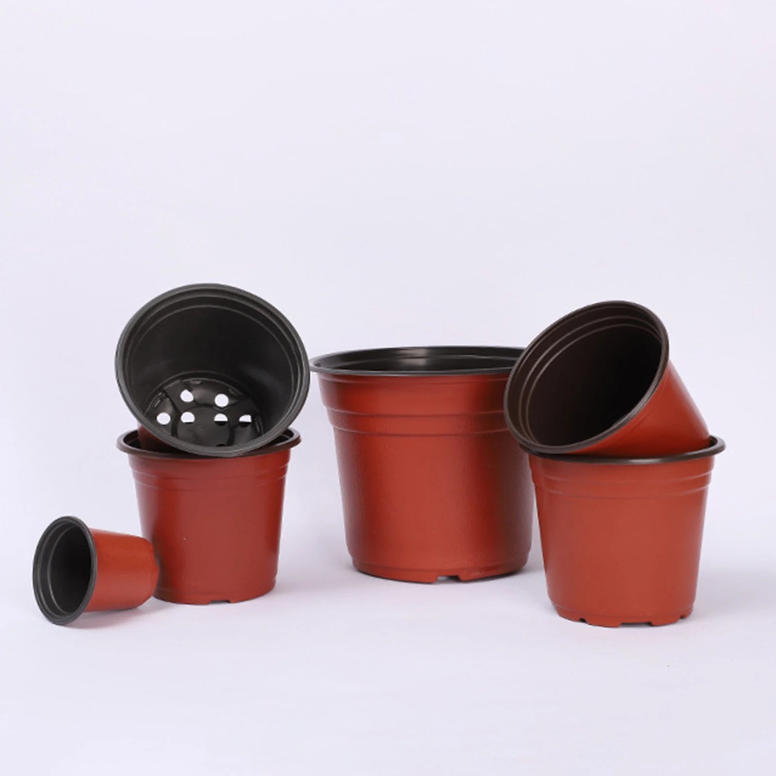 Stacked red plastic nursery pots with black rims and drainage holes